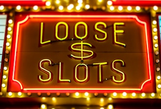 Bright neon lights display the words 'Loose Slots' with a dollar sign in the center. The sign is outlined with bulbs, creating a vibrant and flashy effect typical of a casino or entertainment venue.