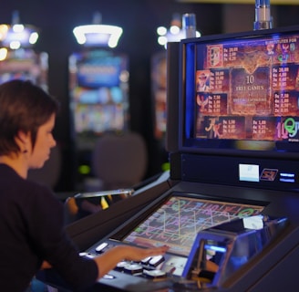 A person is seated at a slot machine console in a casino, focusing intently on the game displayed on the screen. The background shows several other illuminated gaming machines, adding a vibrant and colorful atmosphere to the scene.